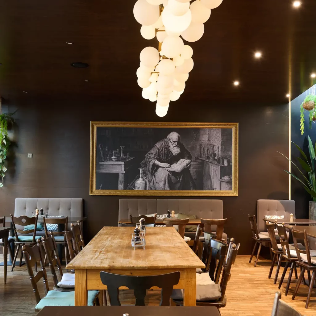 Blick in den Restaurantsaal mit langem Gemeinschaftstisch und Kunstbild an der Wand